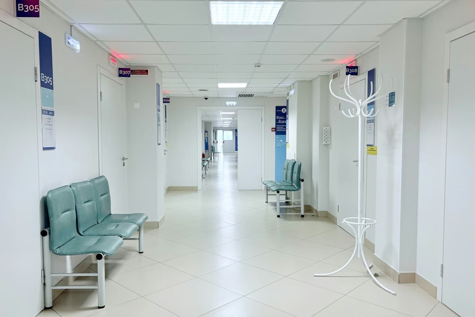 An empty clinic corridor with waiting chairs and consulting room doors